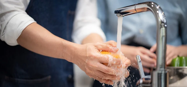  Washing an orange under the sink for household hygiene