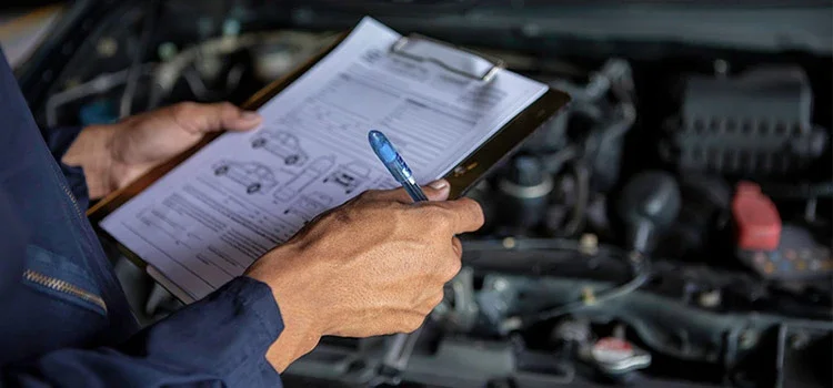  A Mechanic Checking a List of Cars while Servicing a Car in a Garage