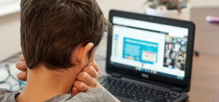 A youngster paying close attention to an online class on his laptop.