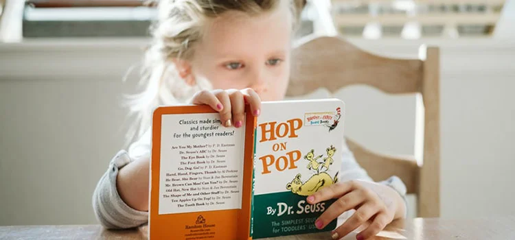 A little girl is enjoying reading a children's picture book by Dr Seuss