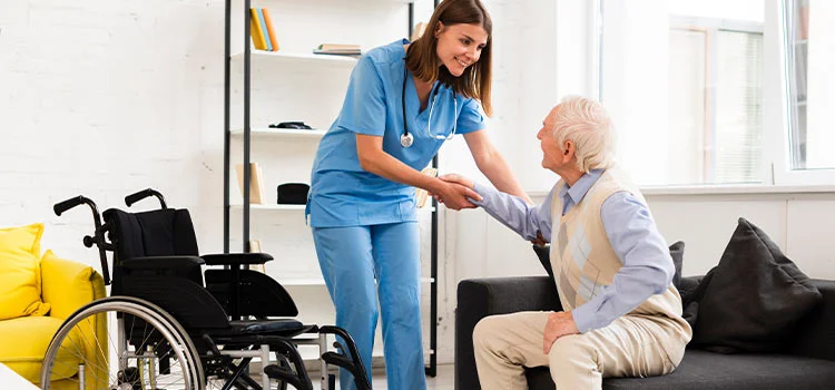 Female carer helping old man getting up.