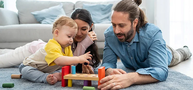 Happy, loving parents engaging in child development while playing with their baby in the living room.