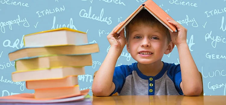 Little boy holding a book above his head, with additional books in front of him and a screen with multiple words behind him.