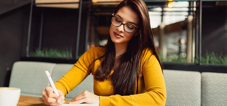 A young journalist sitting on her desk and writing