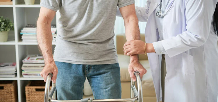 Doctor helping patient to walk with a walking frame