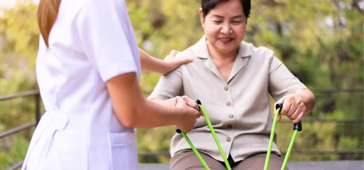 A senior woman is getting help to stretch by a nurse