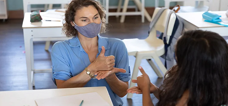 A teacher communicating with her deaf student in classroon