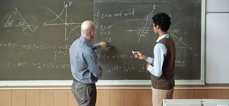 A Teacher Discuss with his Assitant in a Classroom