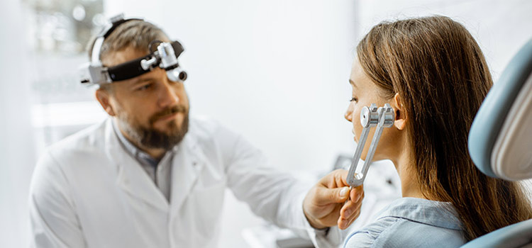 An audiologist doing a hearing test on a patient with tuning fork