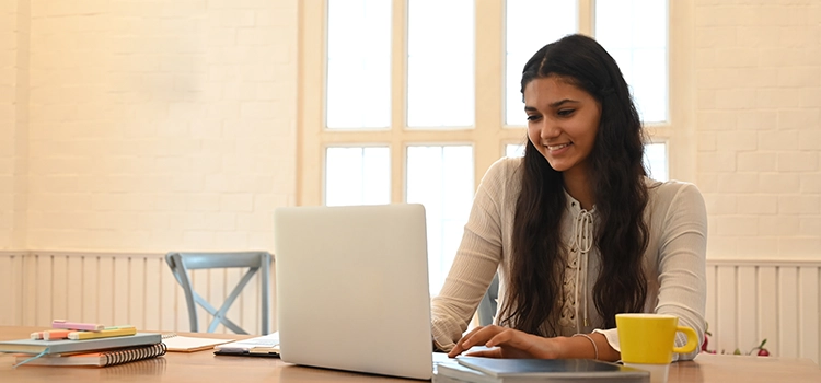 A young female student taking lessons online using a laptop