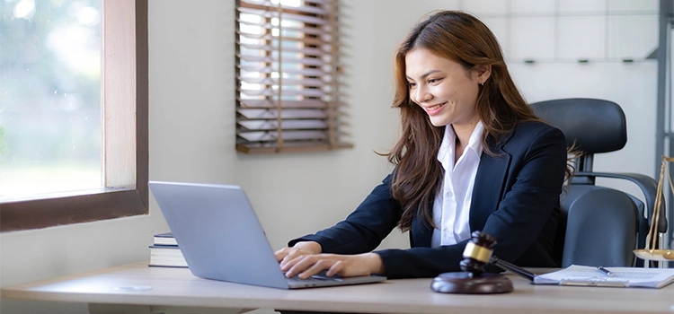 A female lawyer smiling while looking at her laptop screen