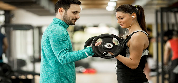Young woman exercising with personal trainer in gym