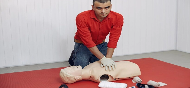 Young person demonstrating CPR on a dummy.