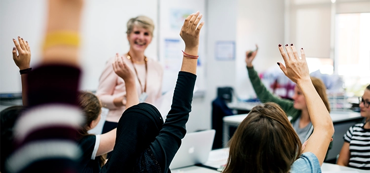 Group of students raising their hands to answer to their teacher (Applicable for QTLS too)