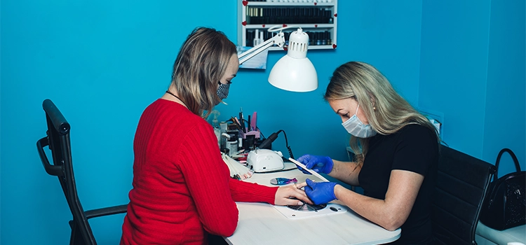 A professional nail tech grooming her client's nails. 