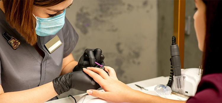 A professional nail artist applying nail polish to her client's fingernails. 