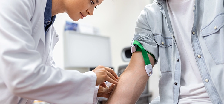 Phlebotomist collecting blood sample from patient with a cannula in hospital.