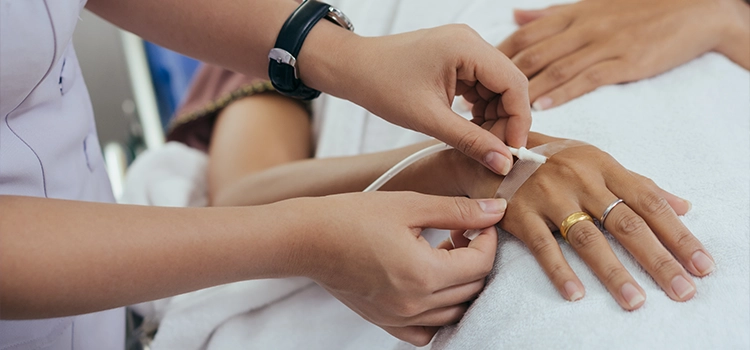 A nurse checking the IV cannula of a patient’s hand.