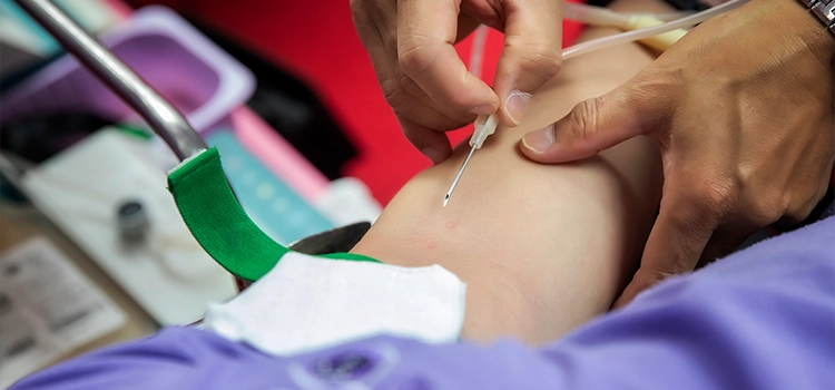 Nurse inserting the needle of a cannula into a patient’s hand. 