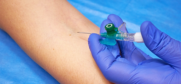 A phlebotomist inserting a cannula into a patient’s forearm. 