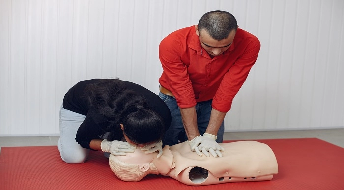 A Group of People Performing CPR on a Dummy During First Aid Training